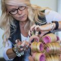 Female hair system technician putting rollers in a female clients hair system
