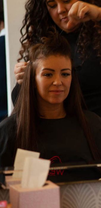 Client with recovering hair loss from chemotherapy watches enhancer system being fitted in mirror