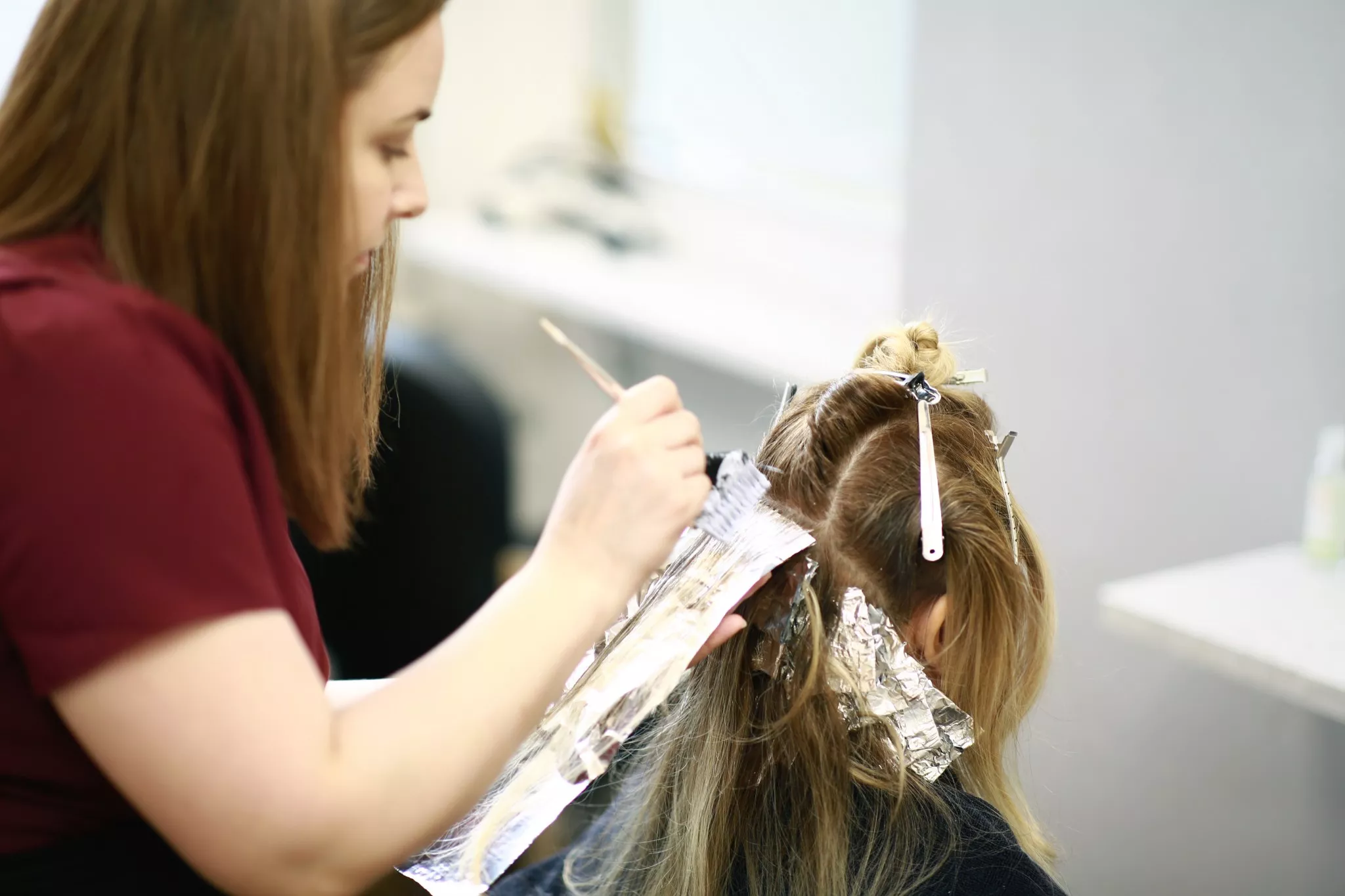Rachael carefully colouring the hair of a female client as part of her stylists role